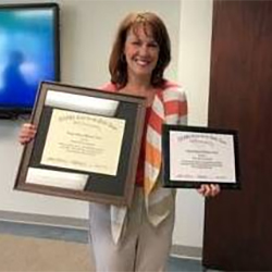 Beth Davis-Sramek holding up the Being a Difference Award.