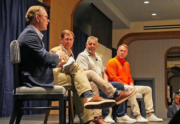 4 men on stage seated talking to audience