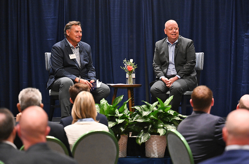 Two men sitting/talking to audience