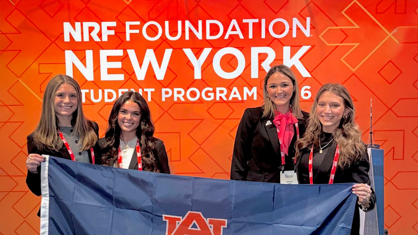 4 women students holding AU sign