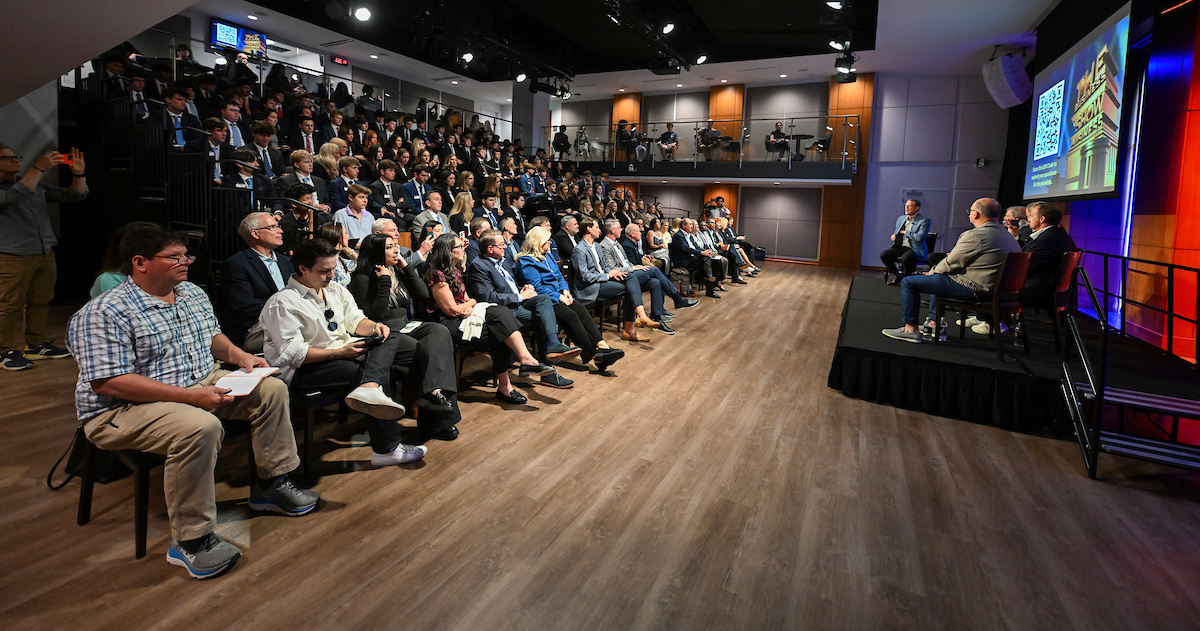 Audience listen to six men on stage