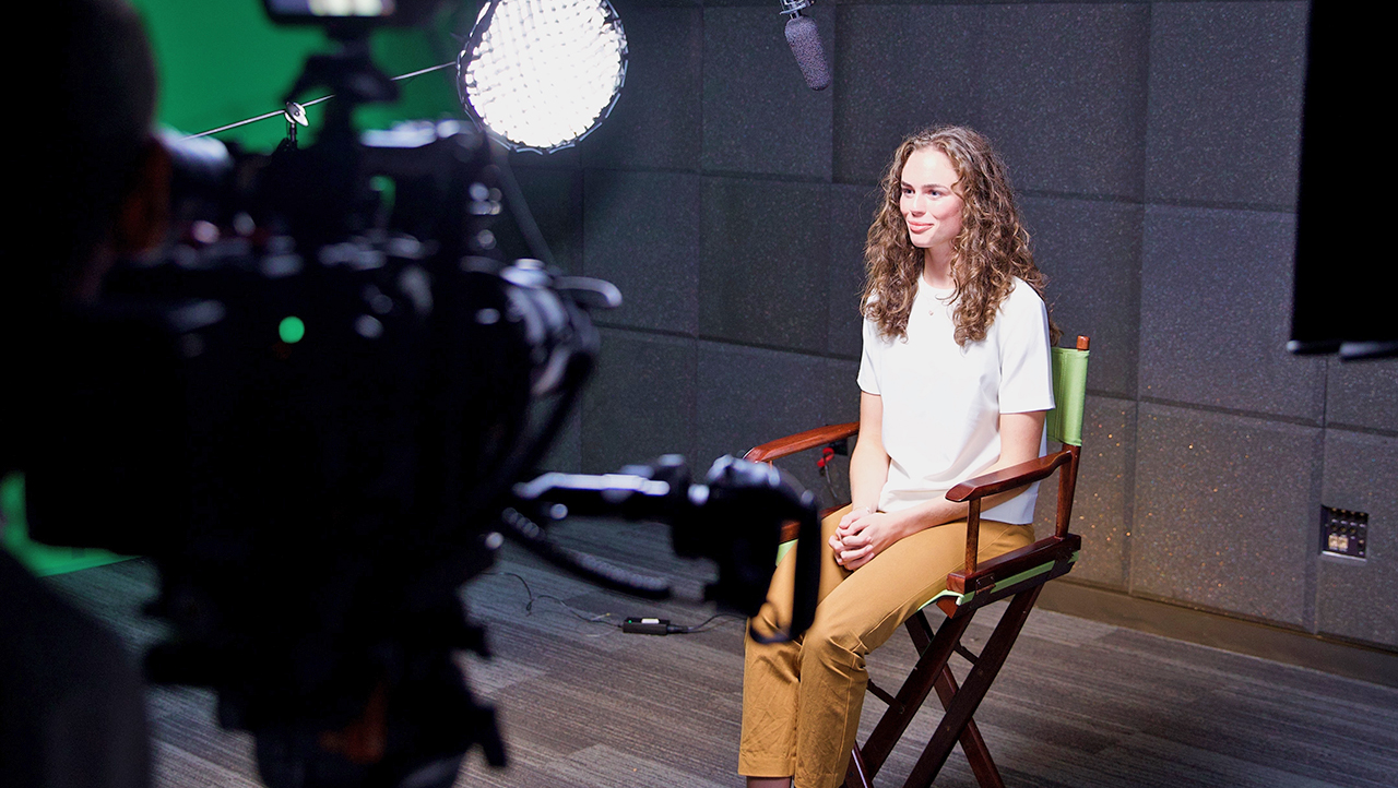 Young woman sitting in chair on soundstage