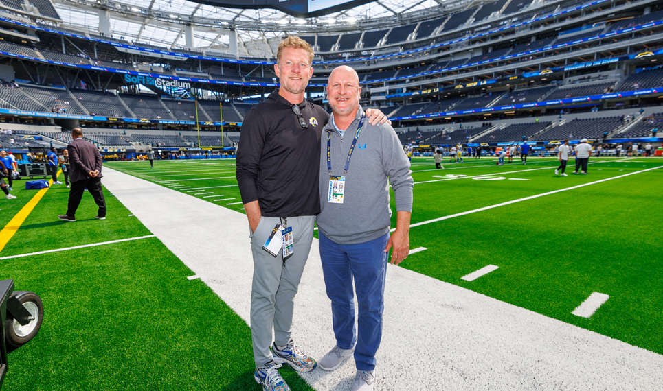 two men standing together on football field