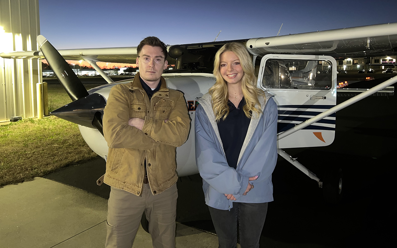 Ethan Franz flight instructor with student standing in front of plane