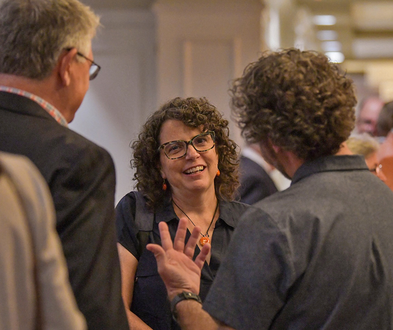 Woman facing camera talking to 2 others