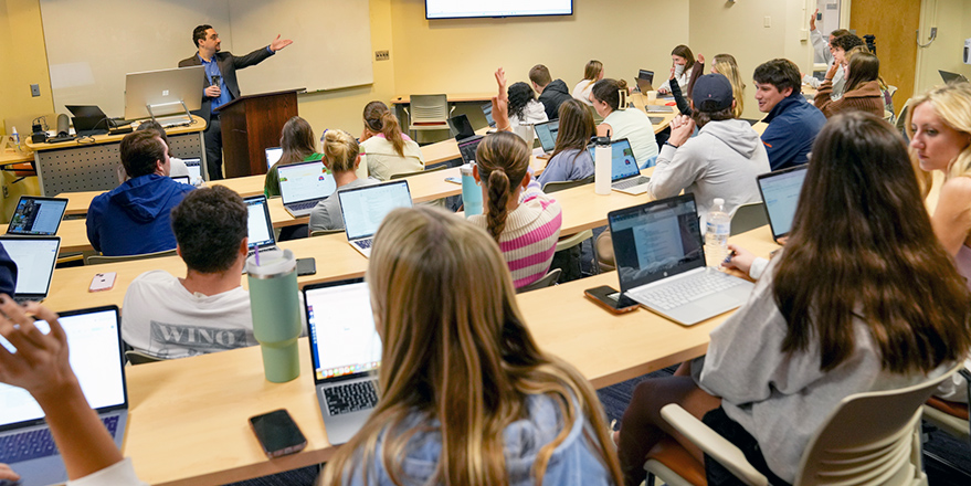 Man teaching students to use software in classroom