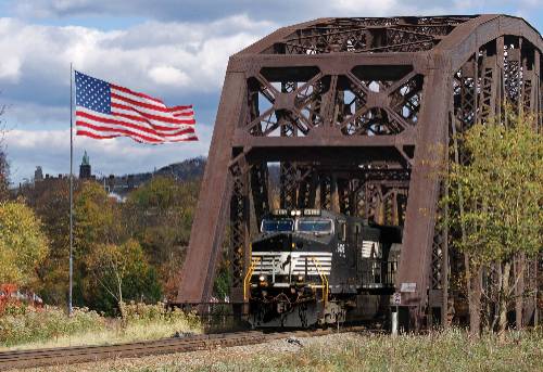 Norfolk Southern train on a bridge next to an American flag