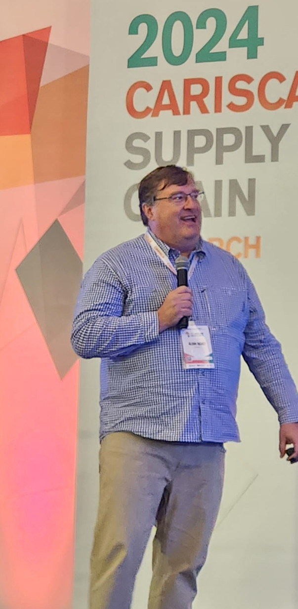 Glenn Richey on stage holding microphone at conference