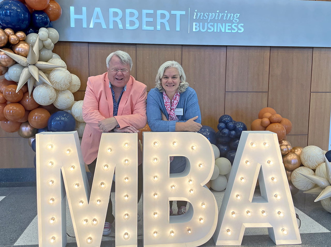 Sarah and Peter Stanwick behind MBA lit sign
