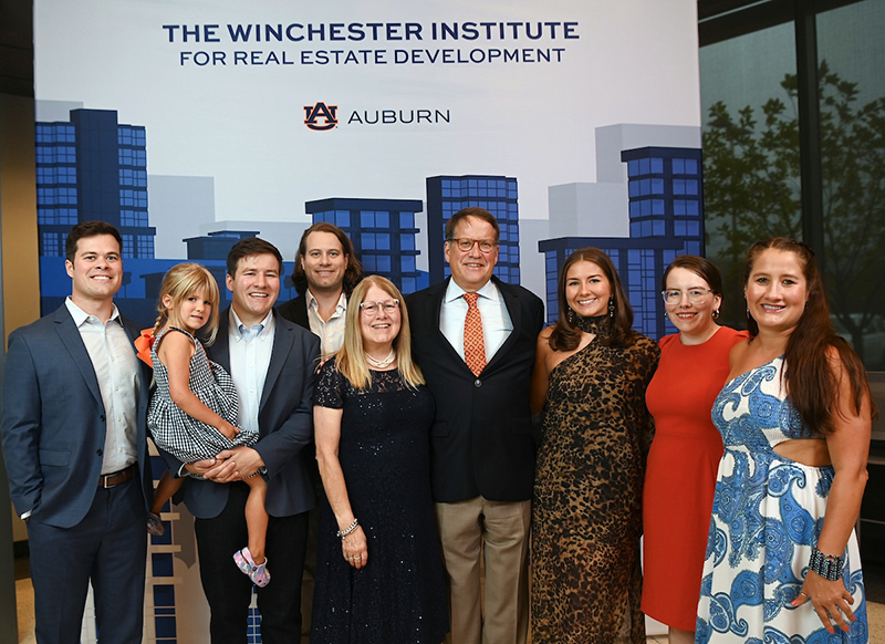Winchester family pose in front of sign