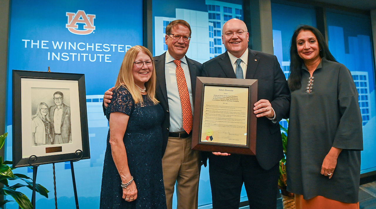Two women, two men standing with plaque