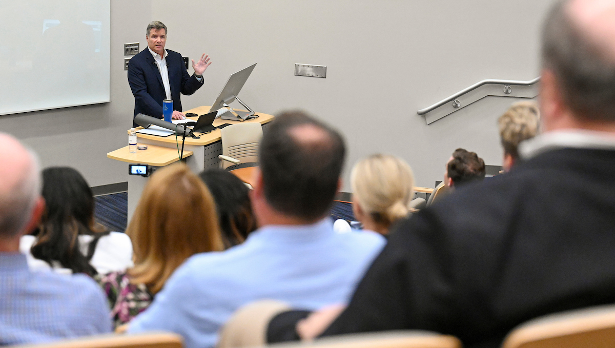 Man lecturing at podium to audience 