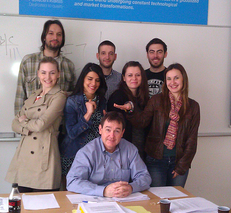 Buter seated, surrounded by students